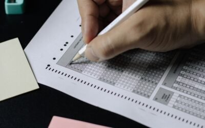 Aspirant filling exam objection form with reference books and laptop